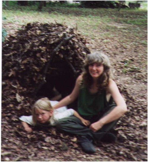 Anneke and Falco camping in leaf shelter they built